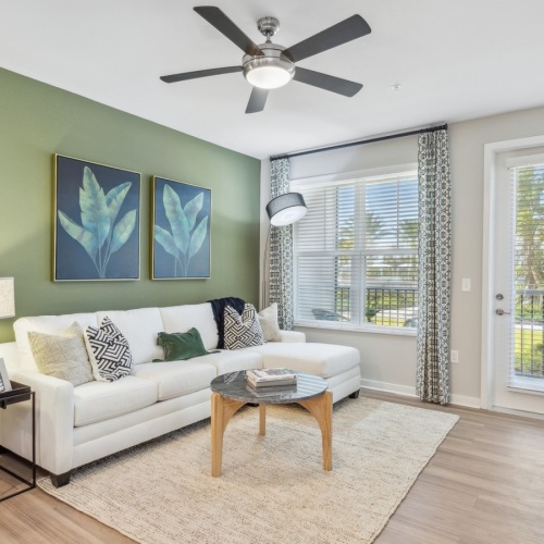 Jacksonville apartment living room featuring a sage green accent wall, chic furnishings, and access to an outdoor patio Jacksonville apartment living room featuring a sage green accent wall, chic furnishings, and access to an outdoor patio