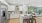 overview of a modern kitchen featuring white cabinets and stainless steel appliances opening up to a living room with a green accent wall